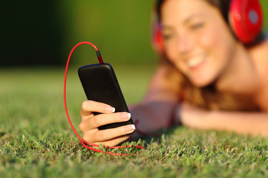 Close up of a woman with headphones holding a smart phone